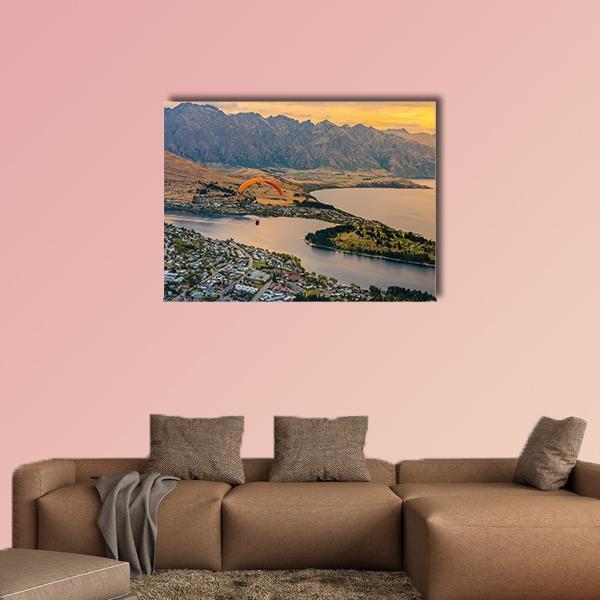 Paraglider Over Queenstown and Lake Wakaitipu Canvas Wall Art in brown, orange and blue, single panel hung on a wall