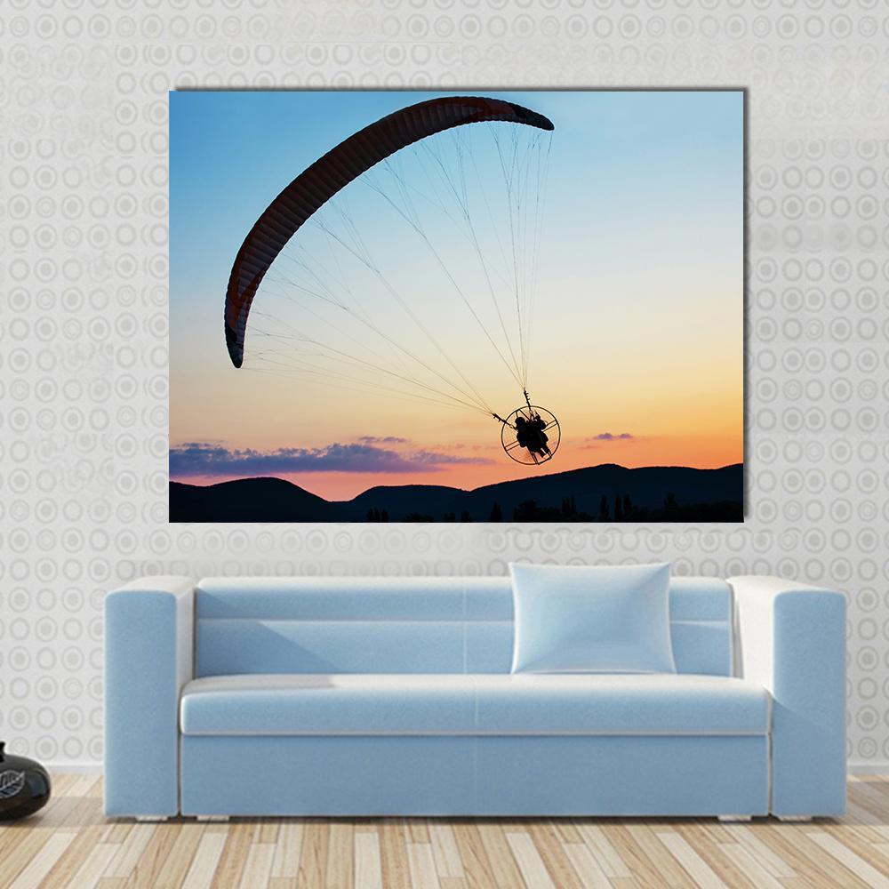 Paragliding Over Hills at Sunset Canvas Wall Art in orange, yellow and blue, single panel hung on a wall
