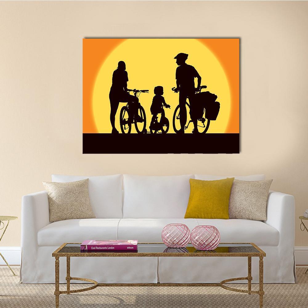 Parents and Child Cycling at Sunset Canvas Wall Art in black, orange and yellow, single panel hung on a wall