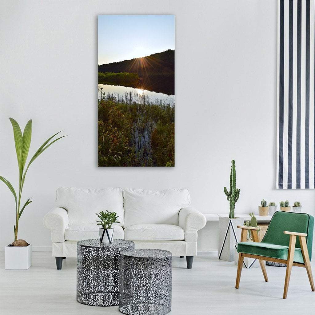 Sunburst Over Lake with Reeds Vertical Canvas Wall Art in black, green and blue, single vertical panel hung on a wall