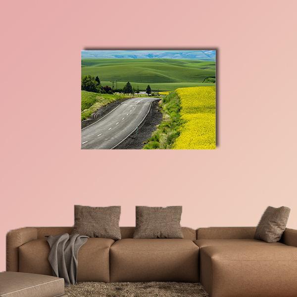 Paved Highway Through Canola Fields Canvas Wall Art in gray, yellow and green, single panel hung on a wall
