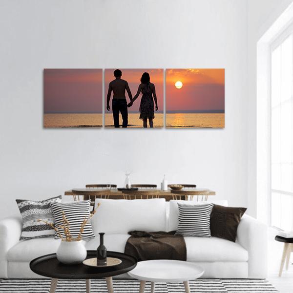 Couple Holding Hands at Sunset Panoramic Canvas Wall Art in black, orange and yellow, hung on a wall