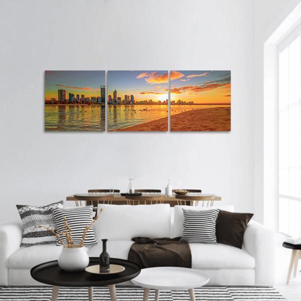Sunset City Skyline with Beach Reflection Panoramic Canvas Wall Art in orange, yellow and blue, hung on a wall