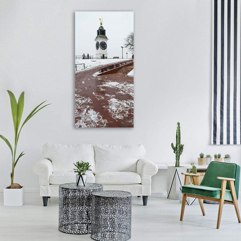 White Clock Tower with Snowy Brick Pathway Vertical Canvas Wall Art in white, gray and brown, single vertical panel hung on a wall