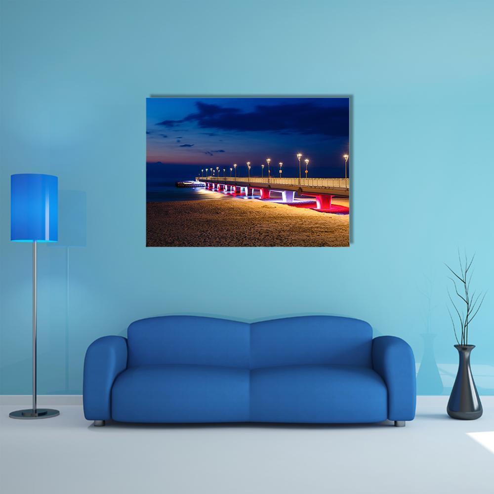 Pier with Glowing Lights at Night Canvas Wall Art in brown, blue and navy, single panel hung on a wall