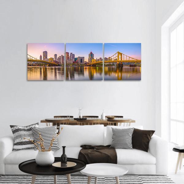 Pittsburgh Skyline Over Allegheny River Panoramic Canvas Wall Art in orange, yellow and blue, hung on a wall