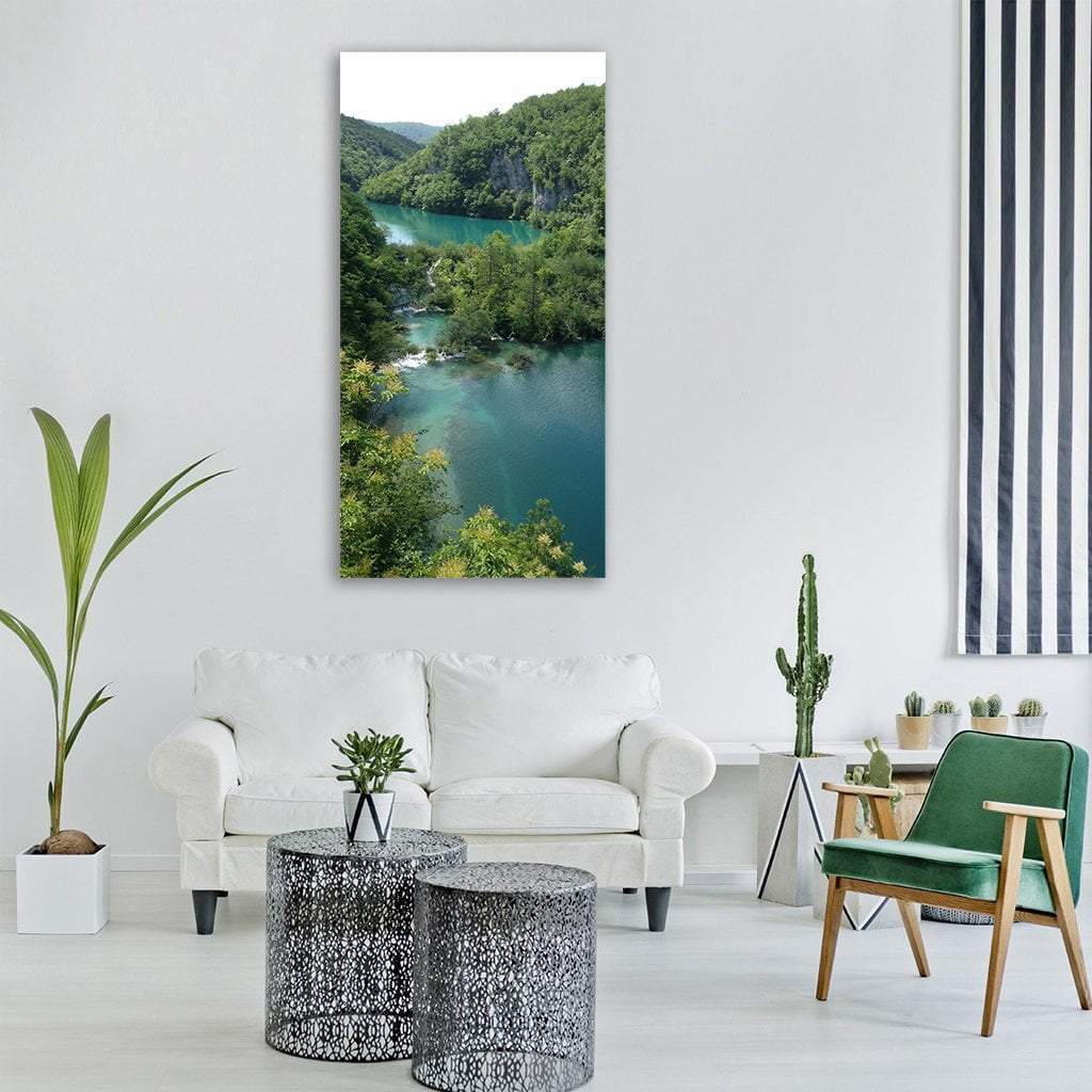 Plitvice Lake Surrounded by Forest Vertical Canvas Wall Art in green and blue, single vertical panel hung on a wall