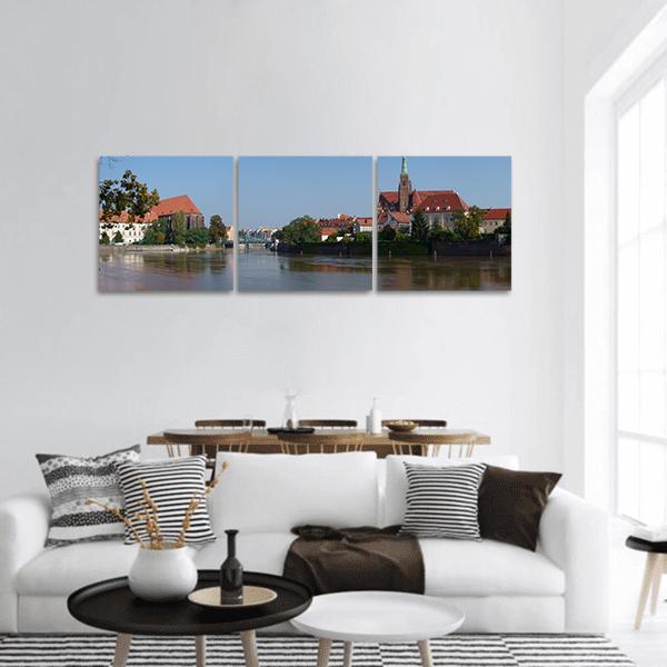 Poland Riverside Cityscape with Green Spire Panoramic Canvas Wall Art in brown, red and blue, hung on a wall