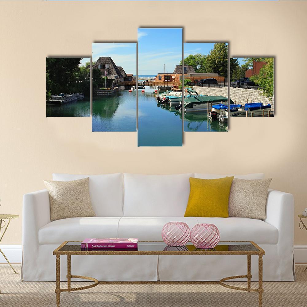 Boats Docked Along Canal with Brown Roofs Canvas Wall Art in brown, green and blue, 5 panel Star layout hung on a wall