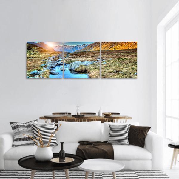 Prairie Sunset Over Mountain Range Panoramic Canvas Wall Art in brown, yellow and blue, hung on a wall