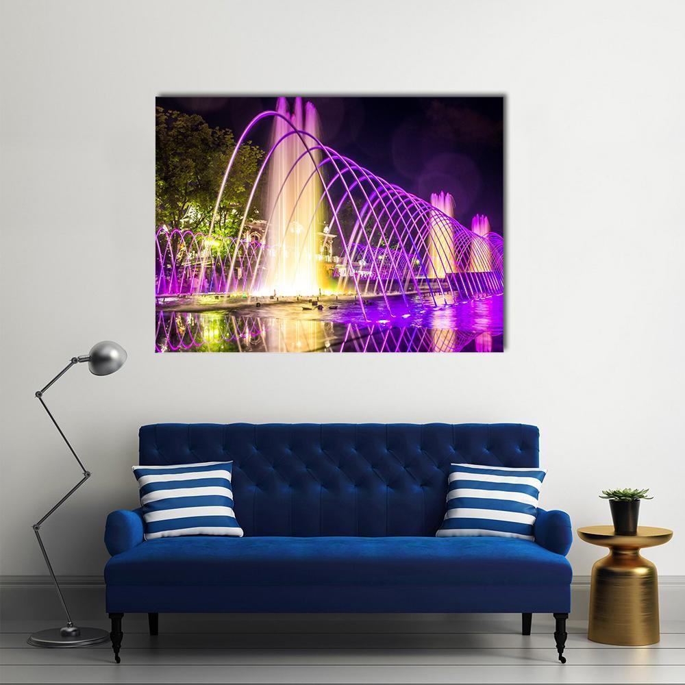 Illuminated Purple Fountains at Night Canvas Wall Art in black, yellow and purple, single panel hung on a wall