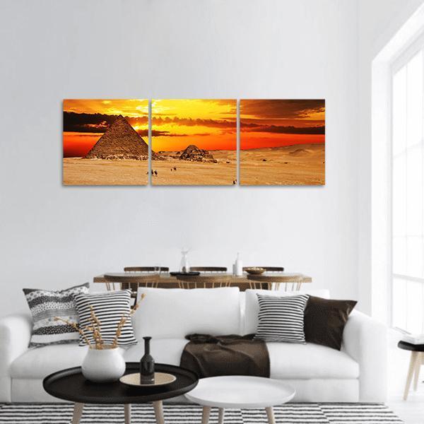 Great Pyramid at Sunset with Camels Panoramic Canvas Wall Art in beige, orange and yellow, hung on a wall