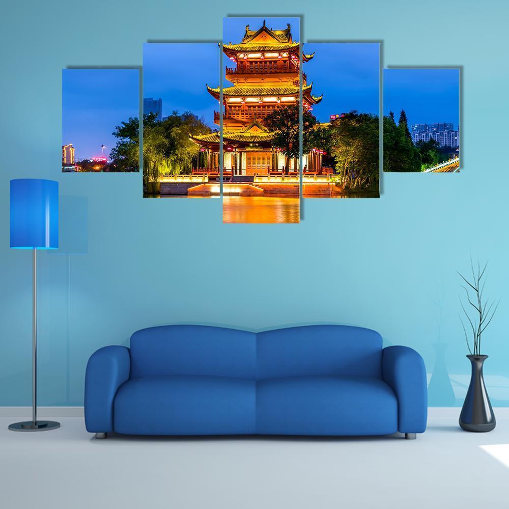 Illuminated Temple Reflected on Water Canvas Wall Art in gold, yellow and blue, 5 panel Star layout hung on a wall