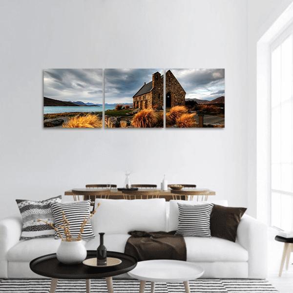 Quiet Church by Glacier Lake Panoramic Canvas Wall Art in gray, brown and blue, hung on a wall