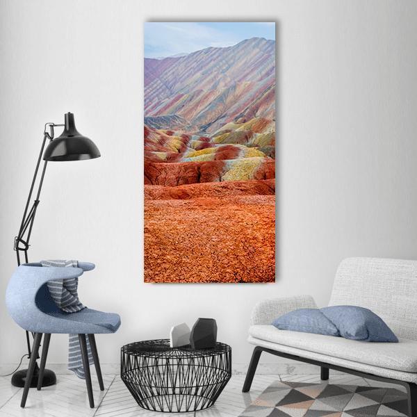 Rainbow Mountains Landscape Vertical Canvas Wall Art in red, orange and multicolor, single vertical panel hung on a wall