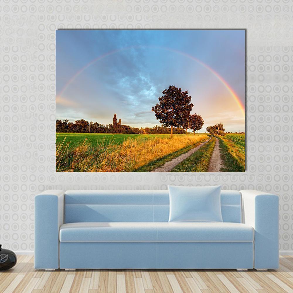 Rainbow Over Field Road Canvas Wall Art in yellow, green and blue, single panel hung on a wall