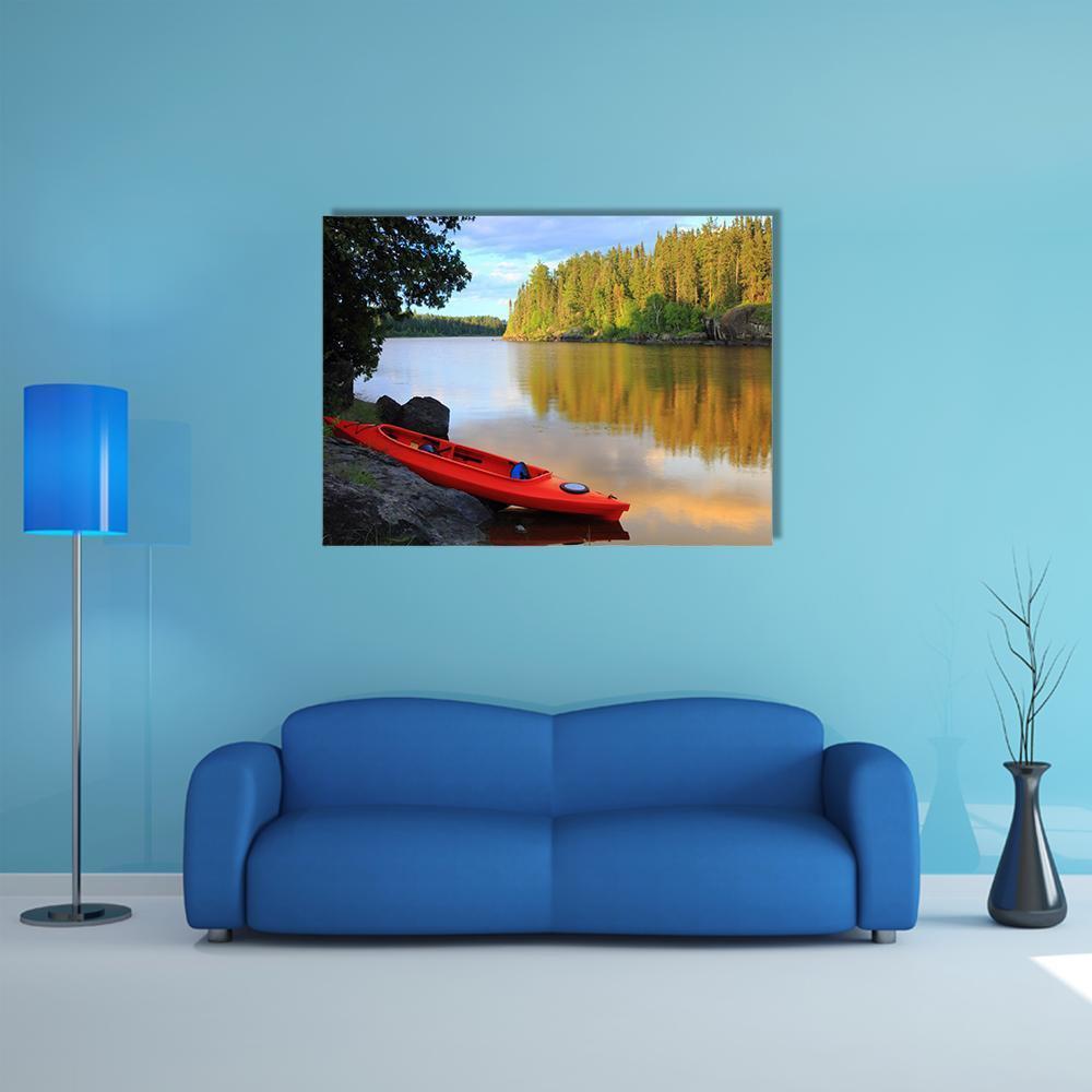 Red Canoe on Rocky Lakeshore at Sunset Canvas Wall Art in orange, yellow and green, single panel hung on a wall