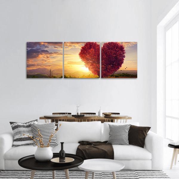 Red Heart-shaped Tree at Sunset Panoramic Canvas Wall Art in red, orange and yellow, hung on a wall