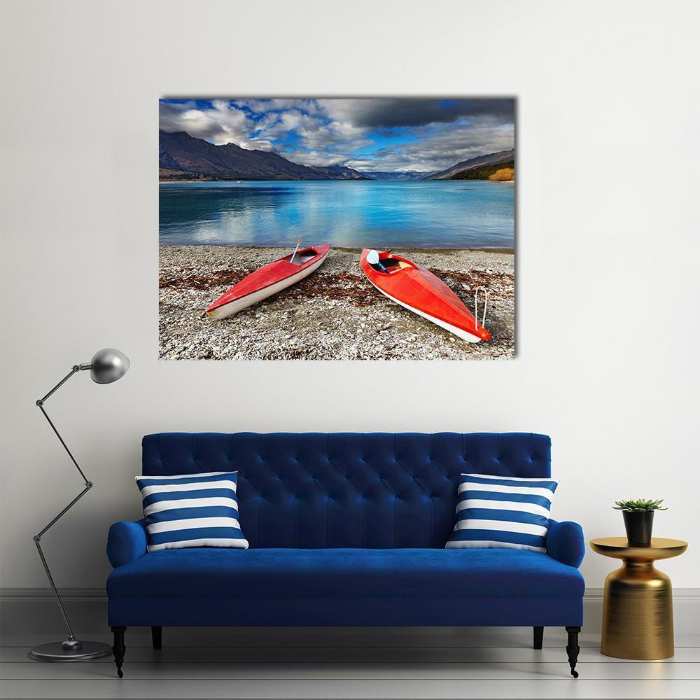 Two Red Kayaks on a Pebbled Lakeshore Canvas Wall Art in gray, red and blue, single panel hung on a wall