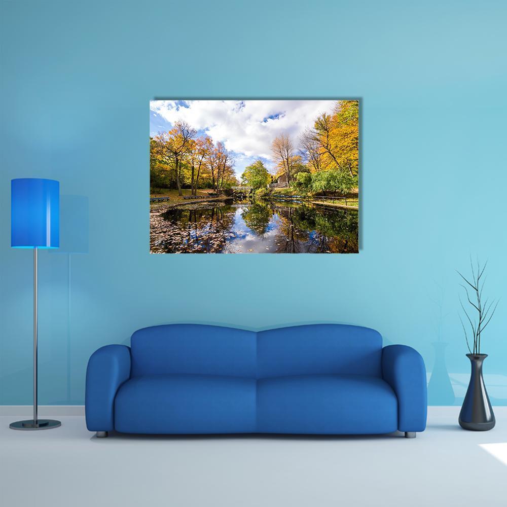 Autumn Trees Reflected in a Lake Canvas Wall Art in orange, yellow and blue, single panel hung on a wall