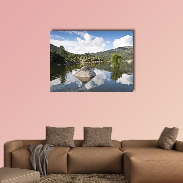 Rock in Lake with Mountain Reflections Canvas Wall Art in gray, green and blue, single panel hung on a wall
