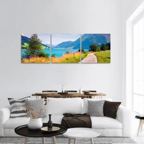 Resia Lake Italian Alps with Winding Path Panoramic Canvas Wall Art in yellow, green and blue, hung on a wall