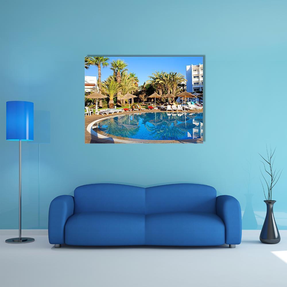 Tropical Resort Swimming Pool Canvas Wall Art in brown, green and blue, single panel hung on a wall