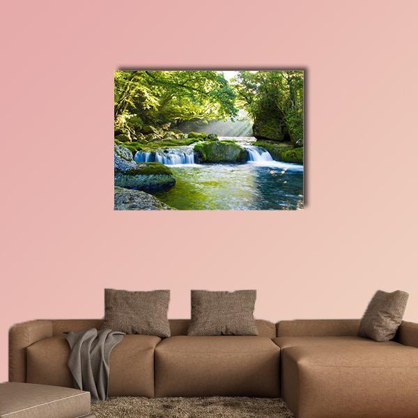 Sunbeams Over River and Mossy Rocks Canvas Wall Art in yellow, green and blue, single panel hung on a wall
