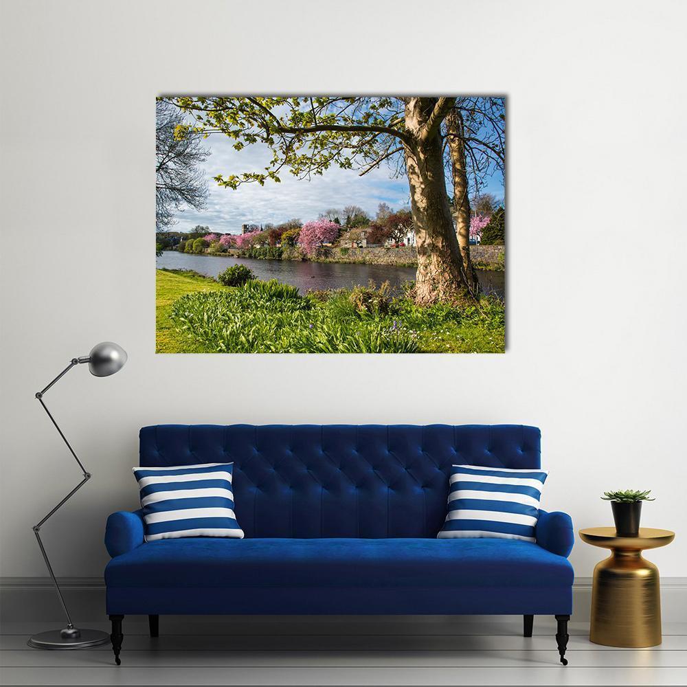 River Cree with Blooming Cherry Trees Canvas Wall Art in green, blue and pink, single panel hung on a wall