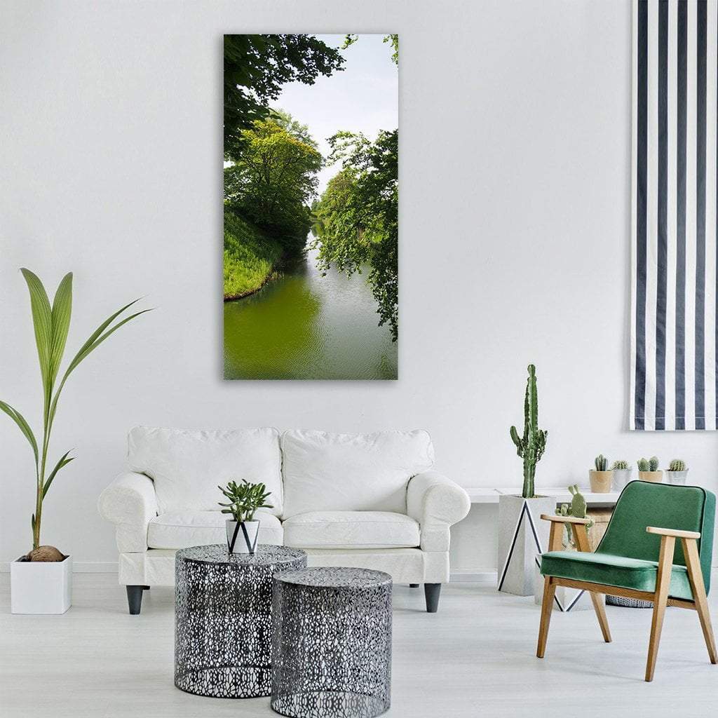 Swedish River with Lush Green Banks Vertical Canvas Wall Art in white and green, single vertical panel hung on a wall