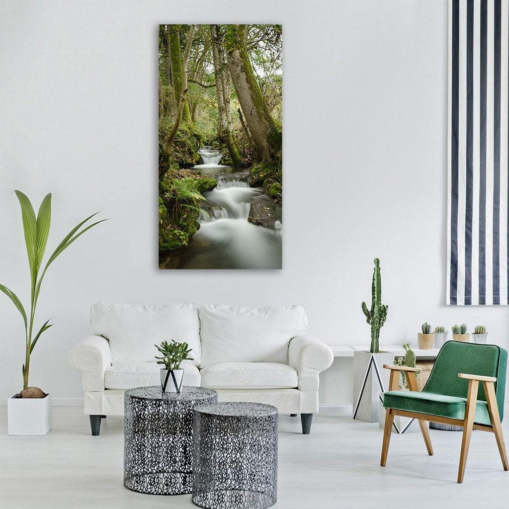 Mossy Forest Stream Long Exposure Vertical Canvas Wall Art in white, brown and green, single vertical panel hung on a wall