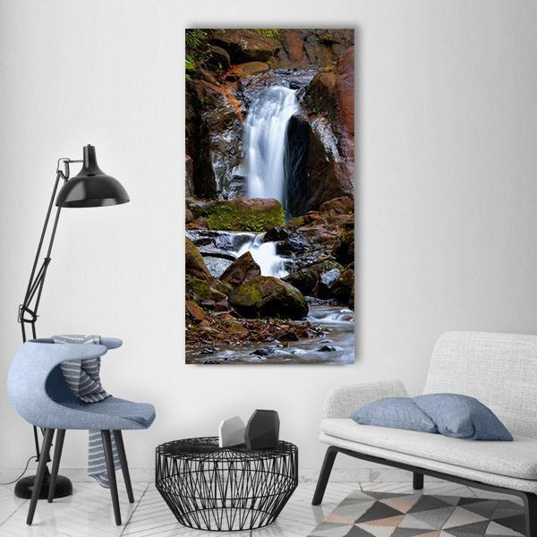 Long Exposure River Waterfall Over Rocks Vertical Canvas Wall Art in white, brown and green, single vertical panel hung on a wall