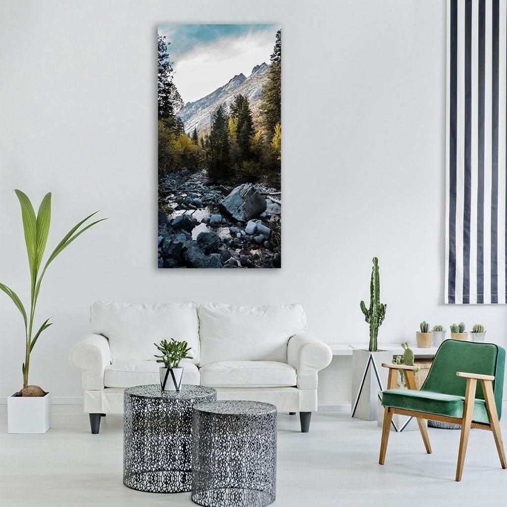 Rocky Mountain River with Pine Trees Vertical Canvas Wall Art in gray, green and blue, single vertical panel hung on a wall