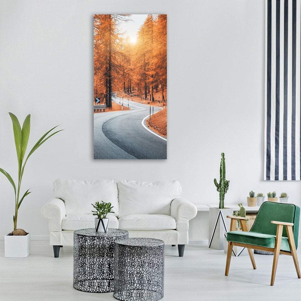 Winding Road Through Autumn Forest at Sunset Vertical Canvas Wall Art in gray, brown and orange, single vertical panel hung on a wall