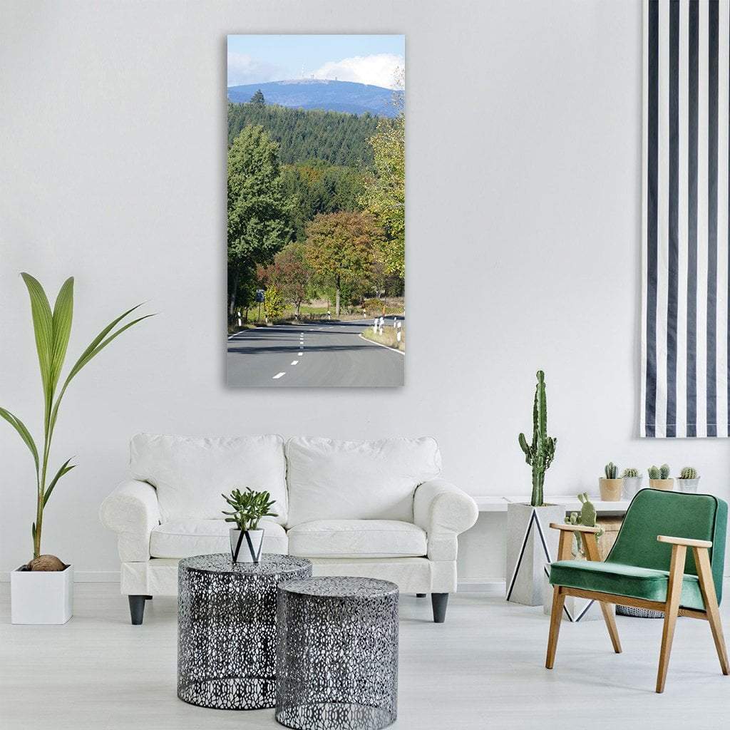 Winding Road Through Autumn Forest Vertical Canvas Wall Art in gray, green and blue, single vertical panel hung on a wall