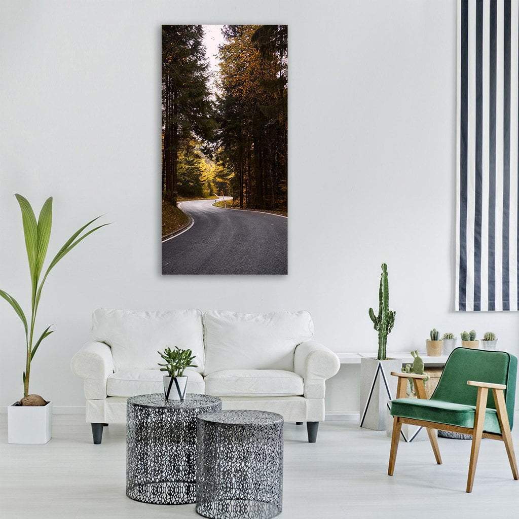 Winding Road Through Autumn Forest Vertical Canvas Wall Art in gray, orange and green, single vertical panel hung on a wall