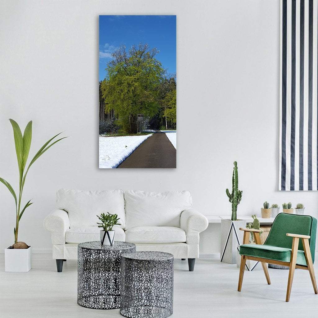 Snow-lined Path with Spring Foliage Vertical Canvas Wall Art in white, green and blue, single vertical panel hung on a wall