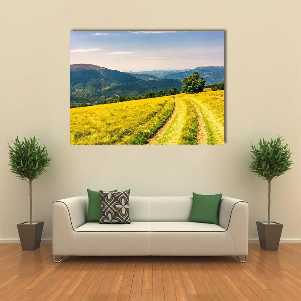 Winding Mountain Road Through Grassy Hills Canvas Wall Art in yellow, green and blue, single panel hung on a wall
