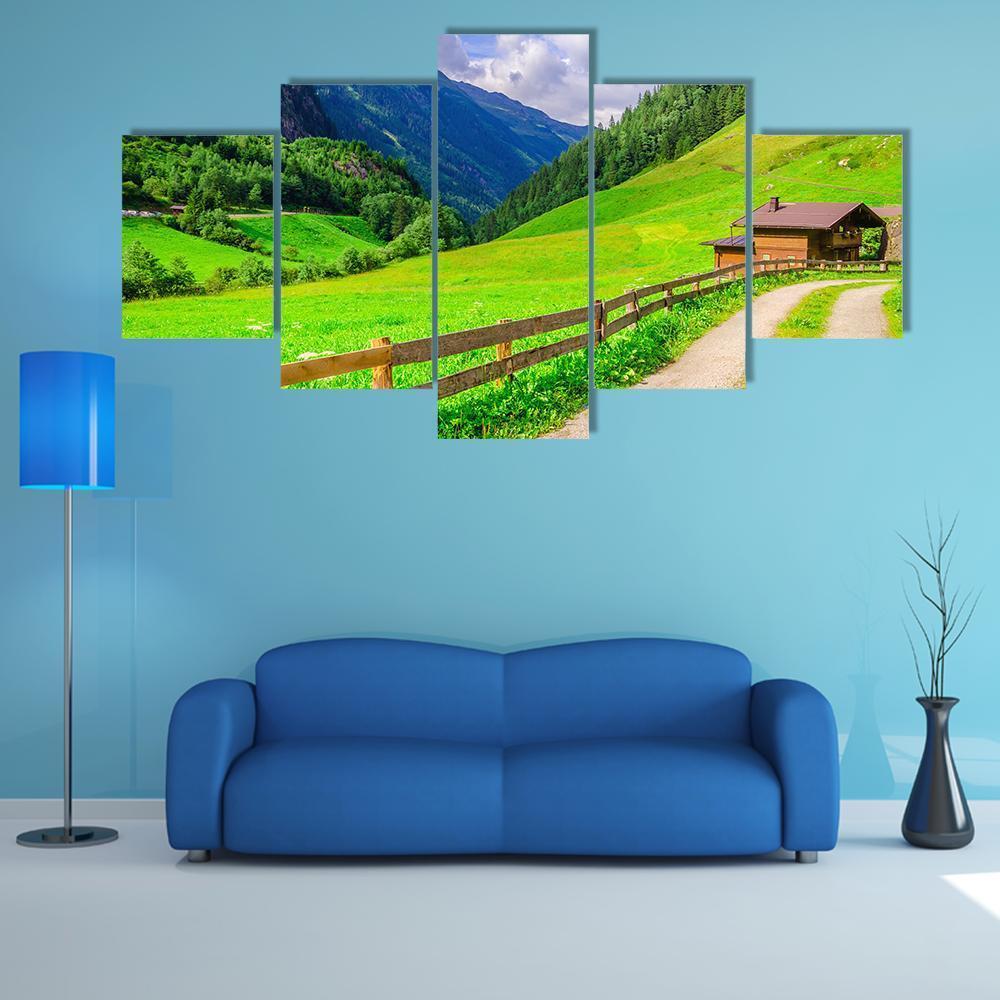 Dirt Road Past Alpine Farmhouses Canvas Wall Art in brown, green and blue, 5 panel Star layout hung on a wall