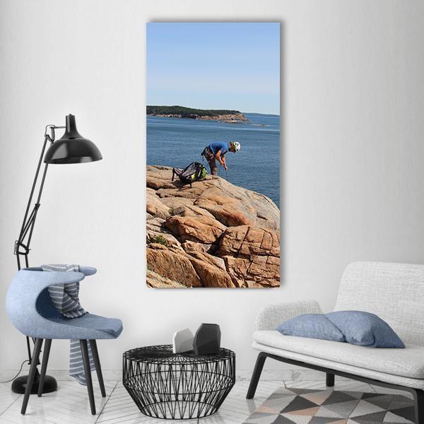 Rock Climber on Coastal Cliffs Vertical Canvas Wall Art in gray, brown and blue, single vertical panel hung on a wall