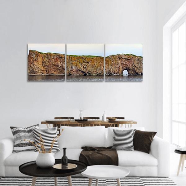 Sea Arch on Grassy Clifftop Panoramic Canvas Wall Art in white, brown and blue, hung on a wall