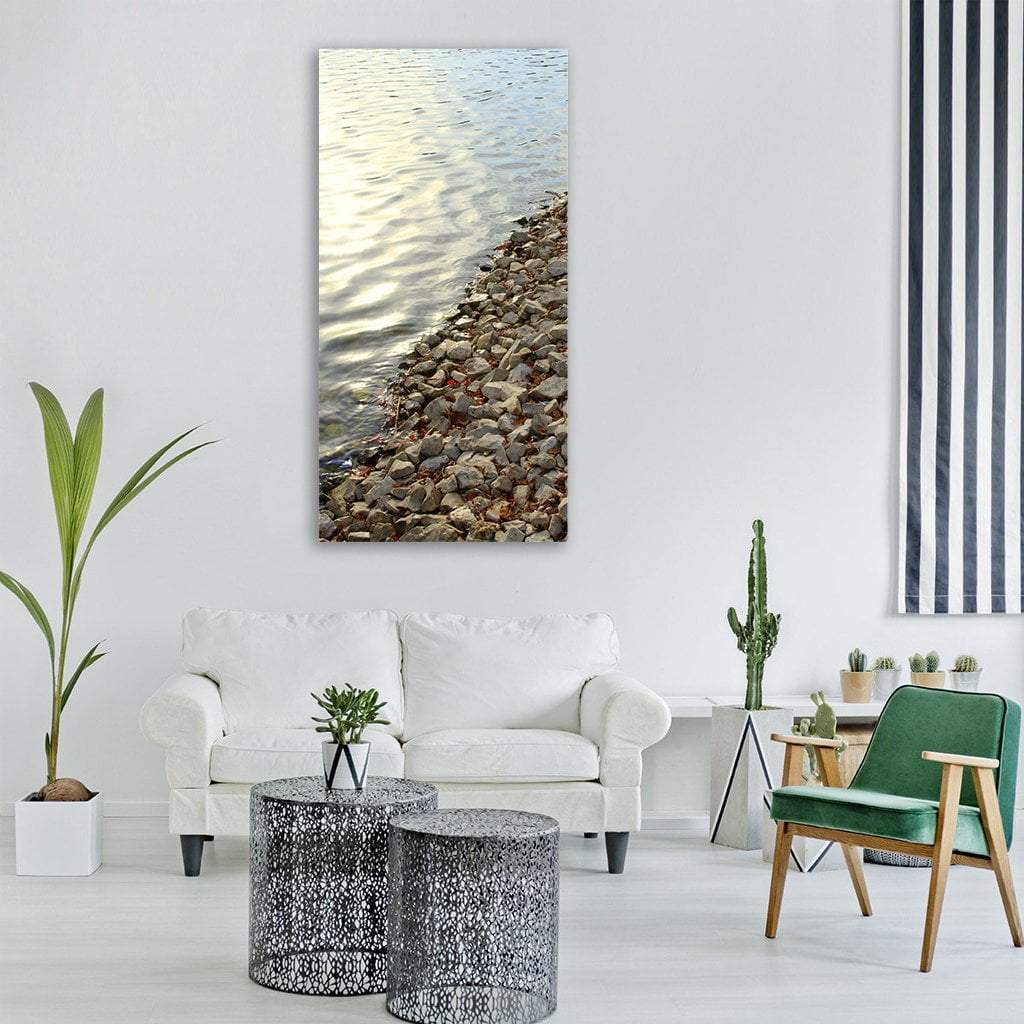 Rocky Lake Shoreline Vertical Canvas Wall Art in gray, brown and blue, single vertical panel hung on a wall