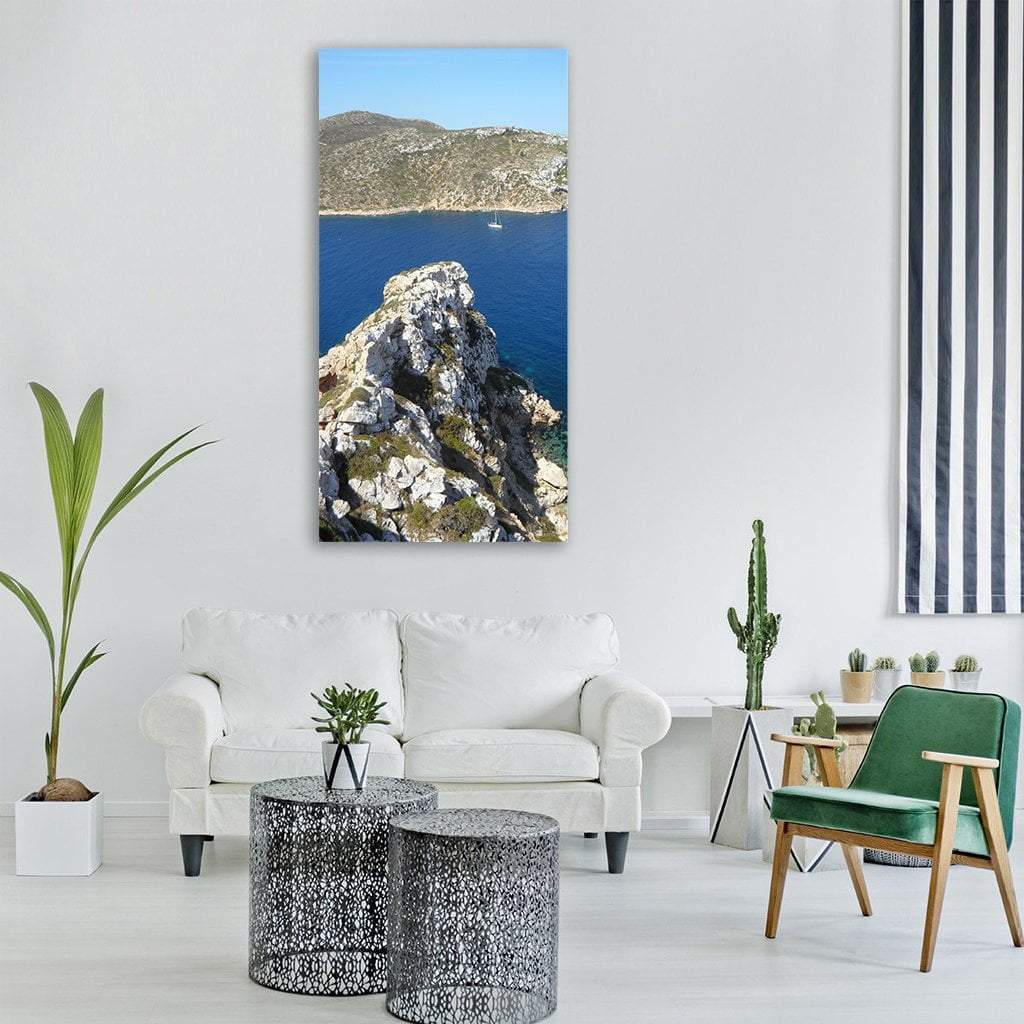 Rocky Coastal Cliff Over Blue Ocean Vertical Canvas Wall Art in gray, green and blue, single vertical panel hung on a wall