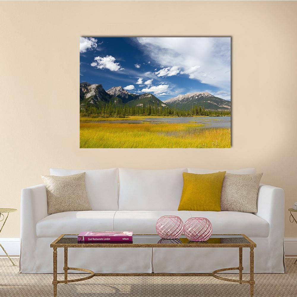 Rocky Mountain Lake with Wispy Clouds Canvas Wall Art in yellow, green and blue, single panel hung on a wall