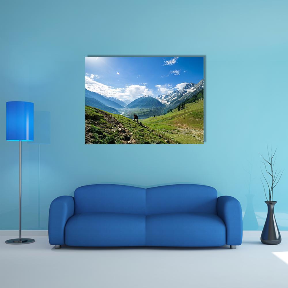 Rocky Mountains Over Green Field with Grazing Animal Canvas Wall Art in green and blue, single panel hung on a wall