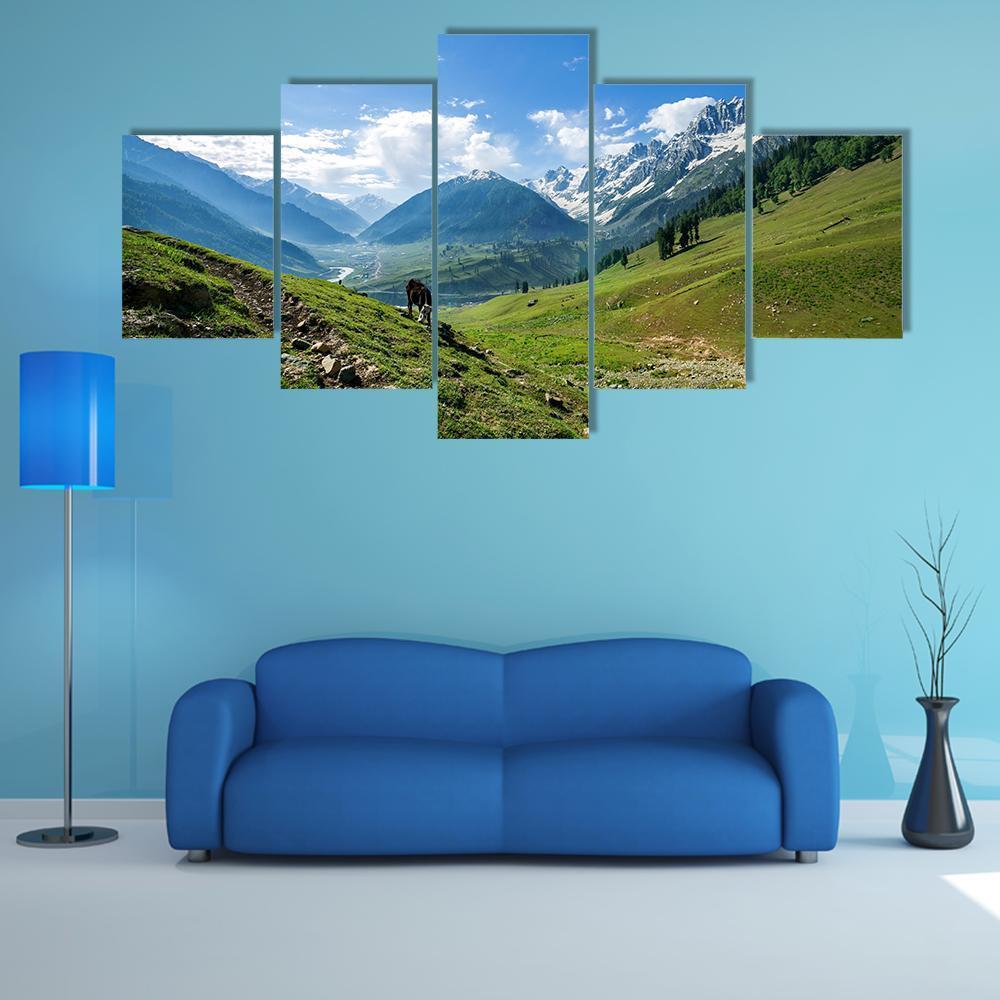 Rocky Mountains Over Green Field with Grazing Animal Canvas Wall Art in green and blue, 5 panel Star layout hung on a wall
