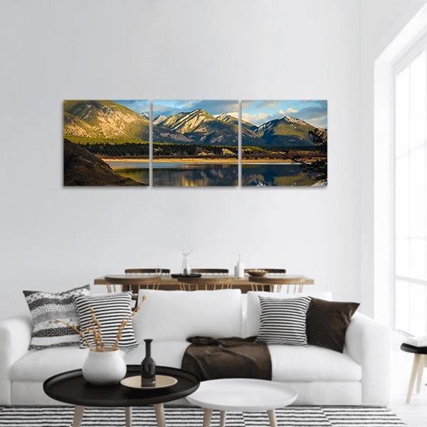 Rocky Mountains with Lake Reflection Panoramic Canvas Wall Art in brown, green and blue, hung on a wall