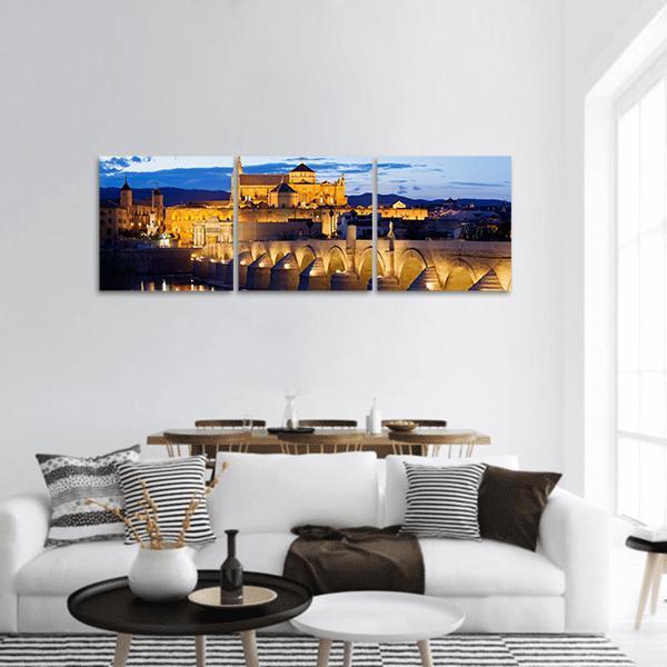 Roman Bridge and Mosque-cathedral of Córdoba Panoramic Canvas Wall Art in orange, yellow and blue, hung on a wall