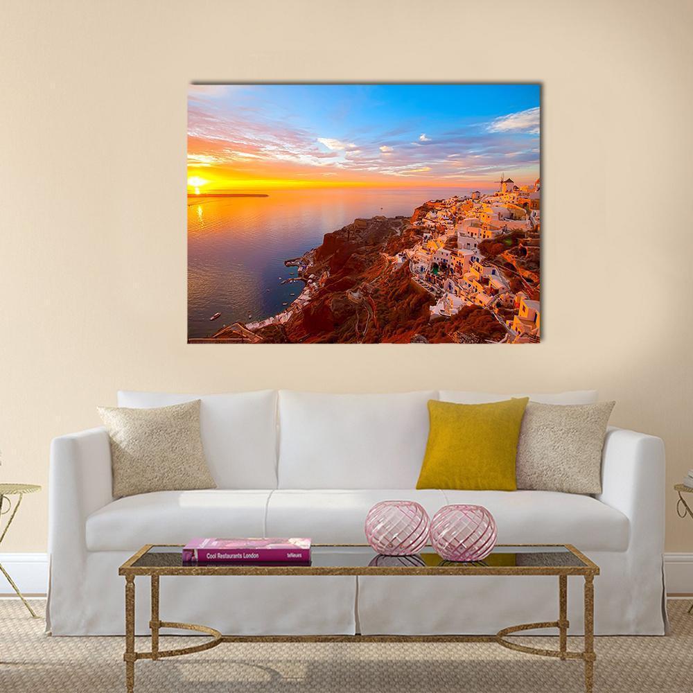 Santorini Sunset Over Coastal Village Canvas Wall Art in orange, yellow and blue, single panel hung on a wall