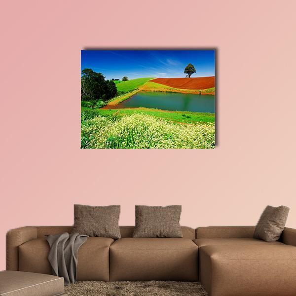 Lone Tree Above Pond in Flowered Field Canvas Wall Art in brown, green and blue, single panel hung on a wall